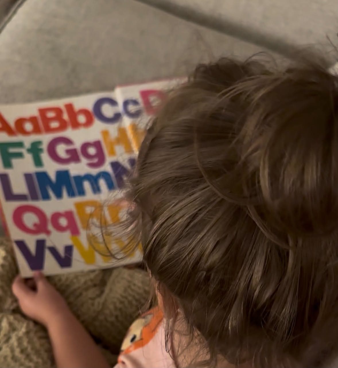 Looking at an alphabet card, seen from behind