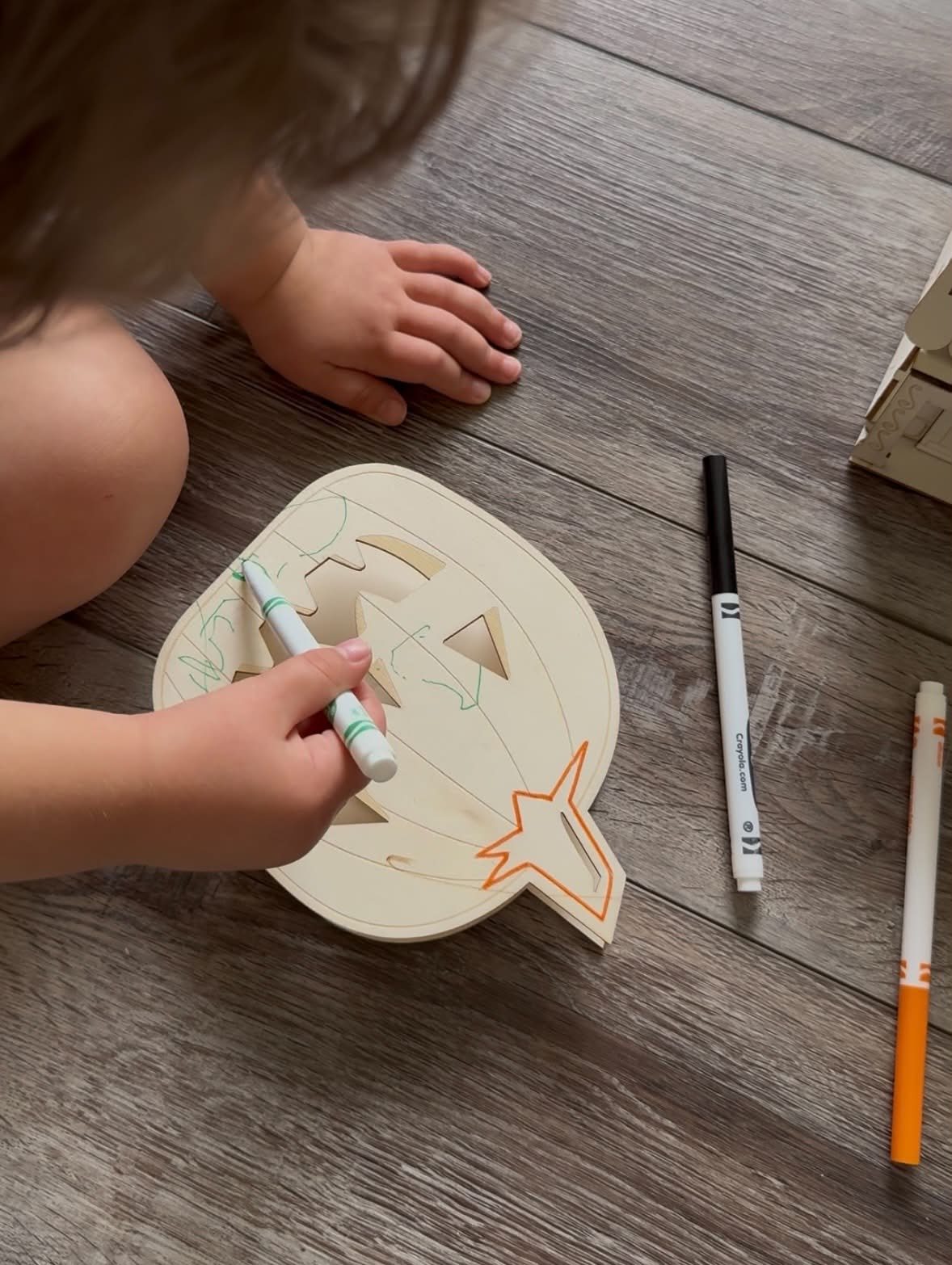 Coloring a wooden pumpkin cutout with markers